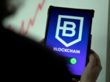 a person holding a cell phone with a blockchain logo on it