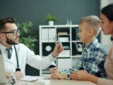 Doctor examines a young boy with his mother present